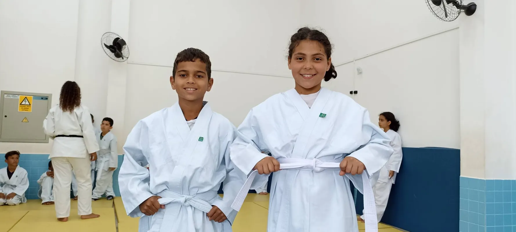 Cesar Samuel da Silva Teles e Vitória Gabriely da Silva, da Escola Municipal Américo Sabino Coimbra, amarram orgulhosos a faixa do quimono: aprender para evoluir