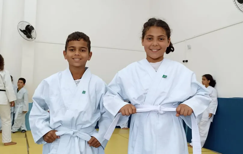 Cesar Samuel da Silva Teles e Vitória Gabriely da Silva, da Escola Municipal Américo Sabino Coimbra, amarram orgulhosos a faixa do quimono: aprender para evoluir