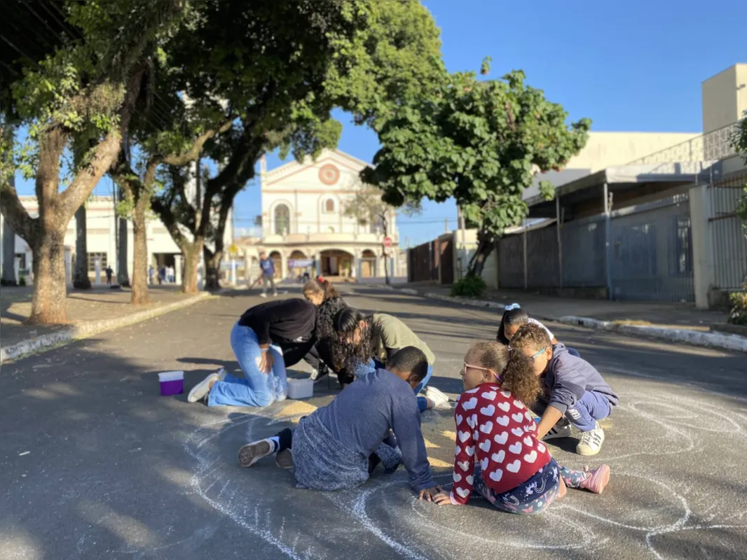 Crianças participam da confecção dos tapetes coloridos perto do Santuário na Vila Nova