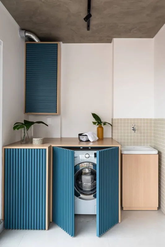 A lavanderia integrada com a área social do apartamento ficou com itens escondidos, como aquecedor e máquina de lavar
