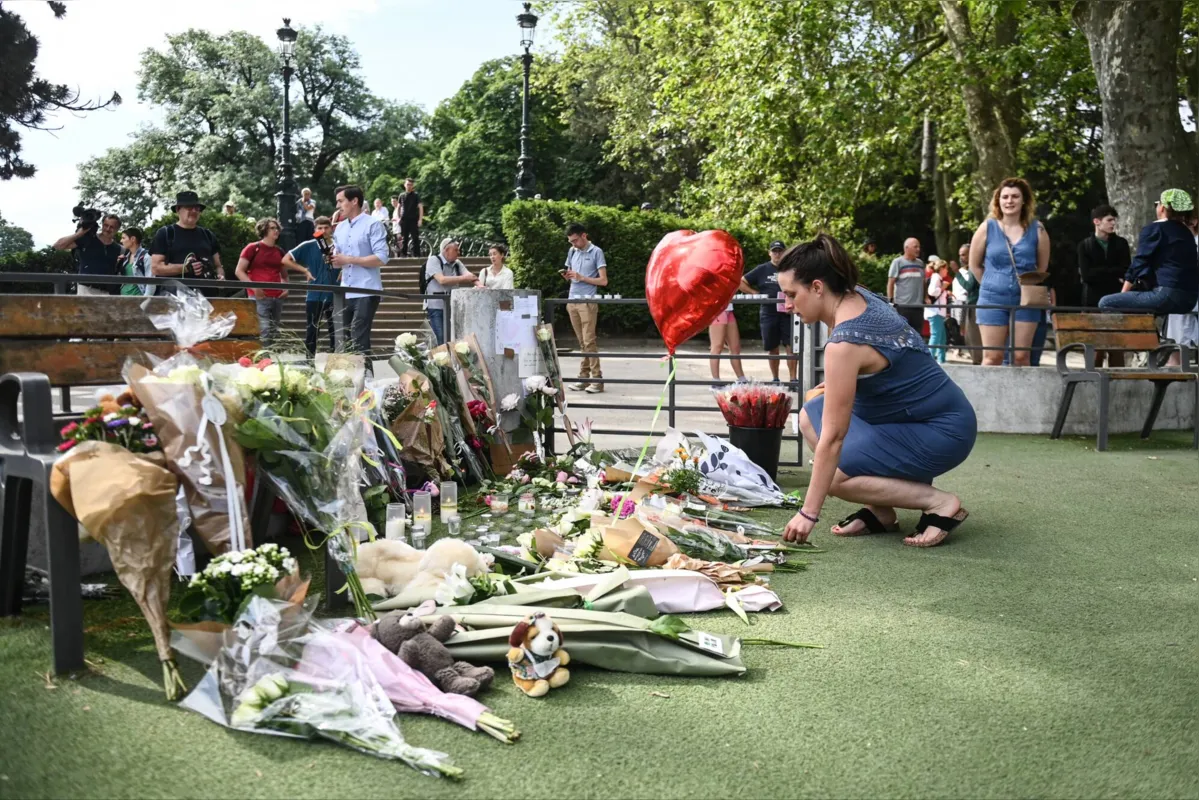 Mulher deixa flores em memorial para as vítimas do ataque  em um parque na cidade de Annecy, nos Alpes Franceses