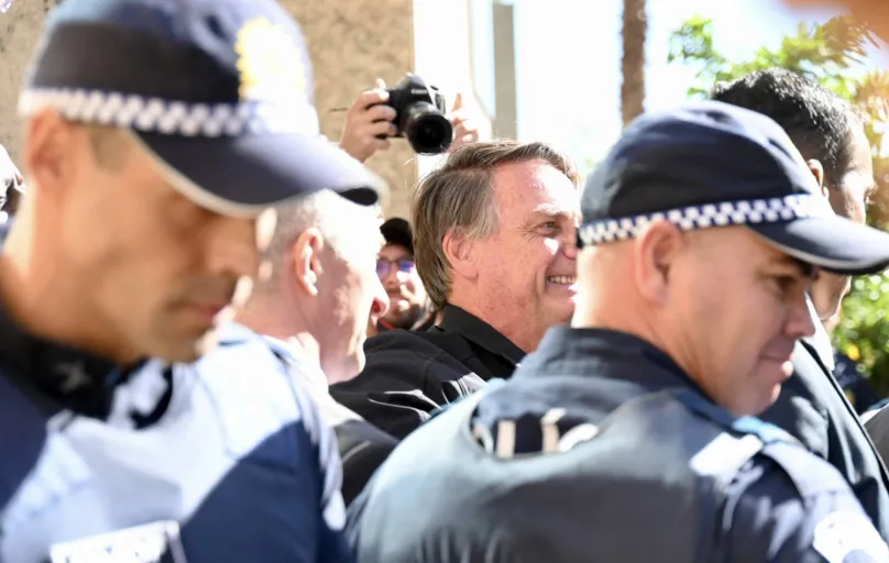 Former Brazilian president Jair Bolsonaro, surrounded by police officers, greets supporters at the Liberal Party headquarters in Brasilia on March 30, 2023. - Disconsolate over his "unjust" defeat in Brazil's divisive 2022 elections, Bolsonaro was uncharacteristically quiet when he slipped out of Brazil in the twilight of his presidential term for a self-imposed exile in Florida. (Photo by Evaristo Juliano DE SA and EVARISTO SA / AFP)
