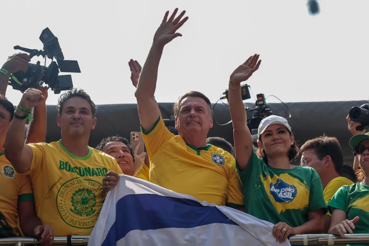 Ao lado da ex-primeira dama, Bolsonaro acena ao público com uma bandeira de Israel