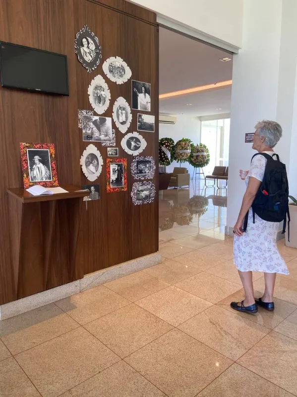 A filha de Nitis Jacon, a antropóloga Gisele Jacon de Araújo Moreira, em frente ao memorial temporário criado para o  velório, com fotos e lembranças da mãe