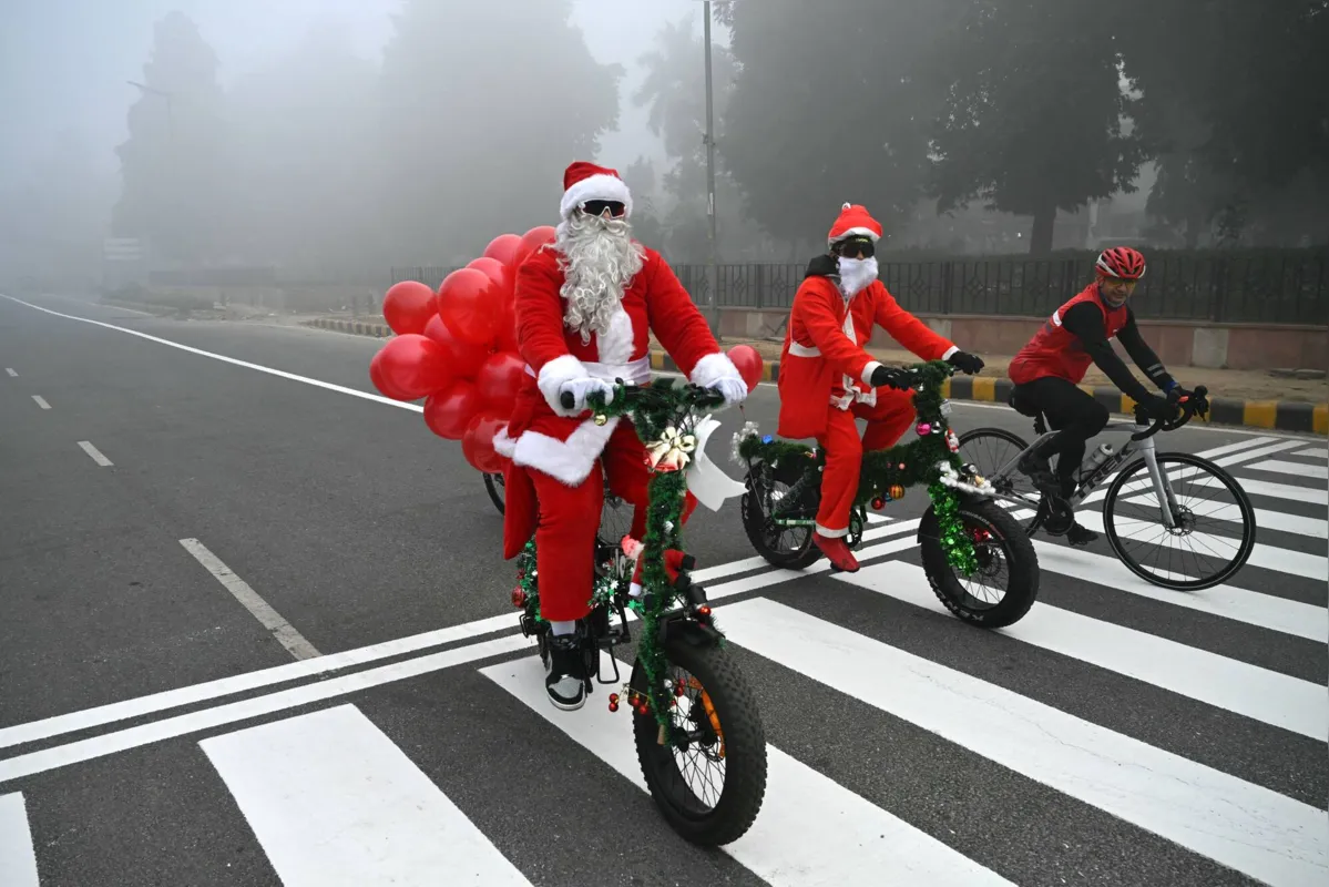 Papai Noel passeia com ciclistas em uma rua de Nova Delhi, Índia