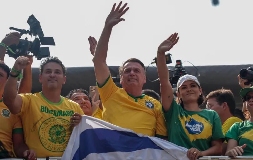 Ao lado da ex-primeira dama, Bolsonaro acena ao público com uma bandeira de Israel