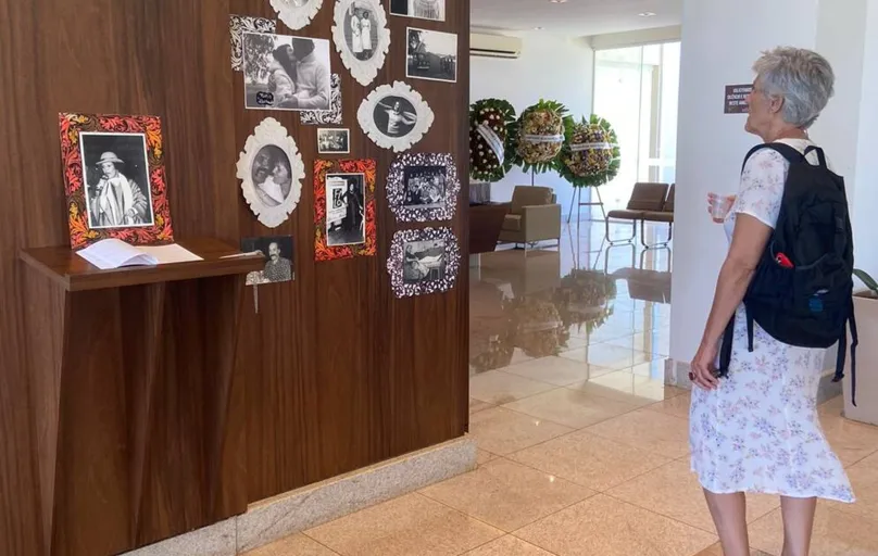 A filha de Nitis Jacon, a antropóloga Gisele Jacon de Araújo Moreira, em frente ao memorial temporário criado para o  velório, com fotos e lembranças da mãe