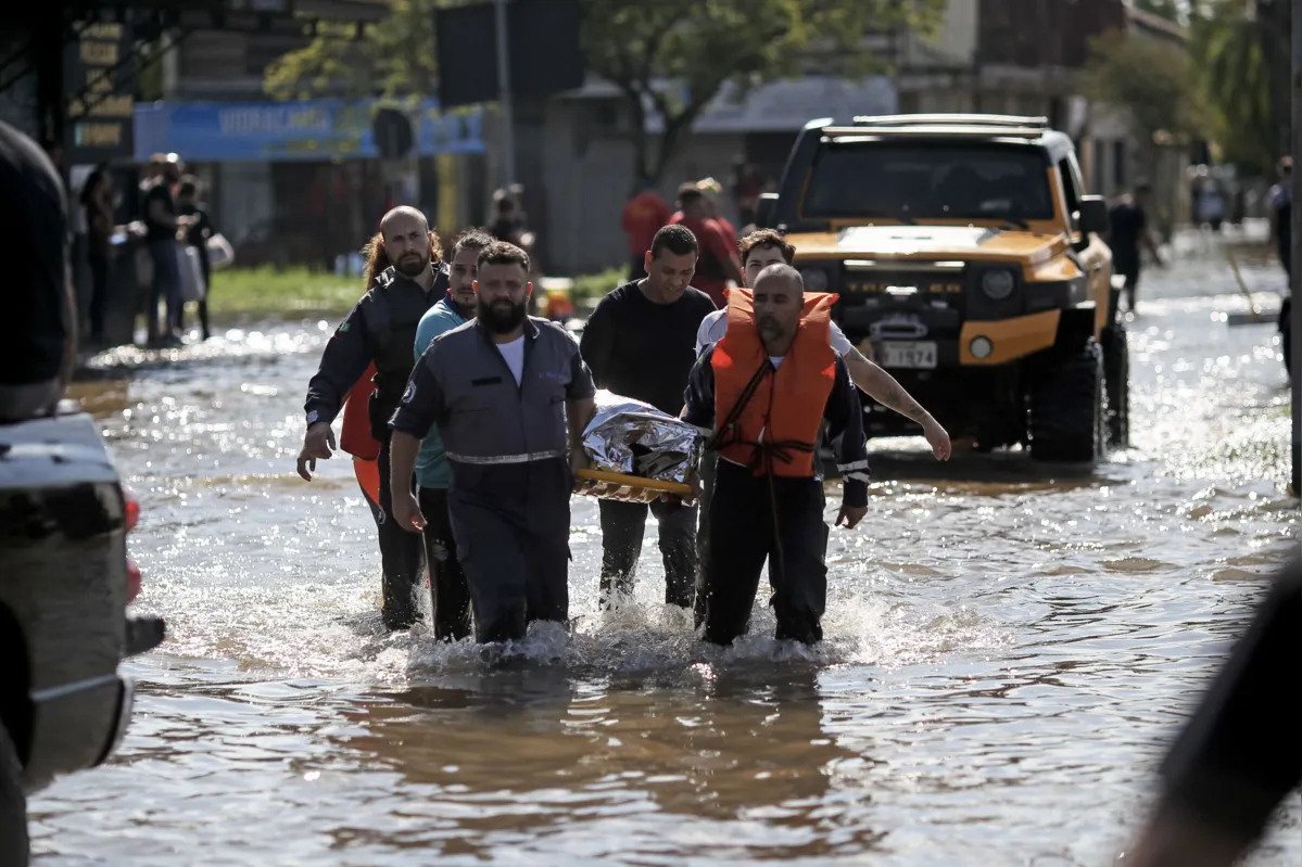 A woman is transported to a medical center after being rescued at the Sarandi neighbourhood in Porto Alegre, Rio Grande do Sul state, Brazil on May 5, 2024. The challenge is titanic and against the clock: authorities and neighbours are trying to avoid an even greater tragedy than the one already experienced in the Brazilian state of Rio Grande do Sul, where 66 people died and 80,000 were displaced by the floods, according to the authorities. (Photo by Anselmo Cunha / AFP)