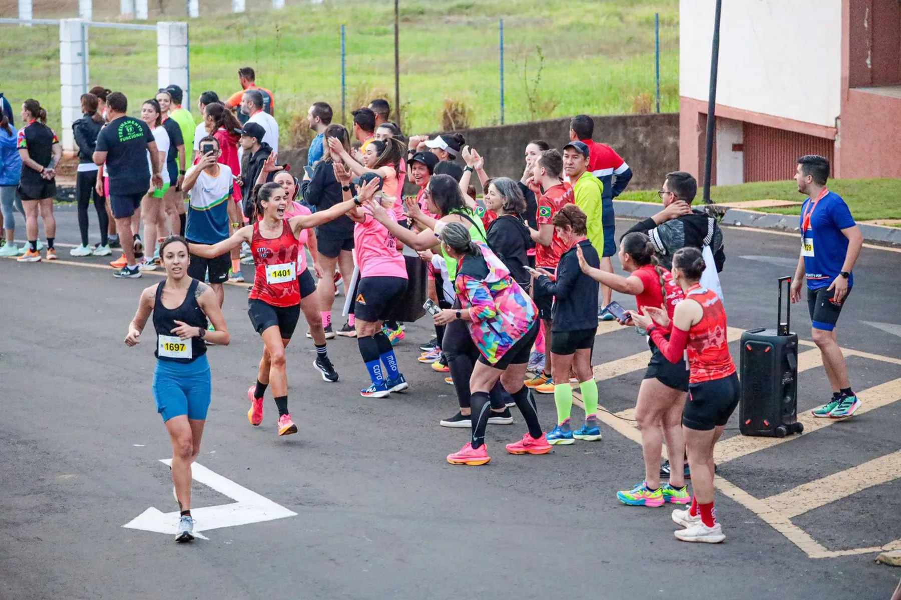 Natalia Melo Couga Rosa, de vermelho, acenando, é fundadora  da marca Caramelo, uma referência em camisetas e acessórios de corrida