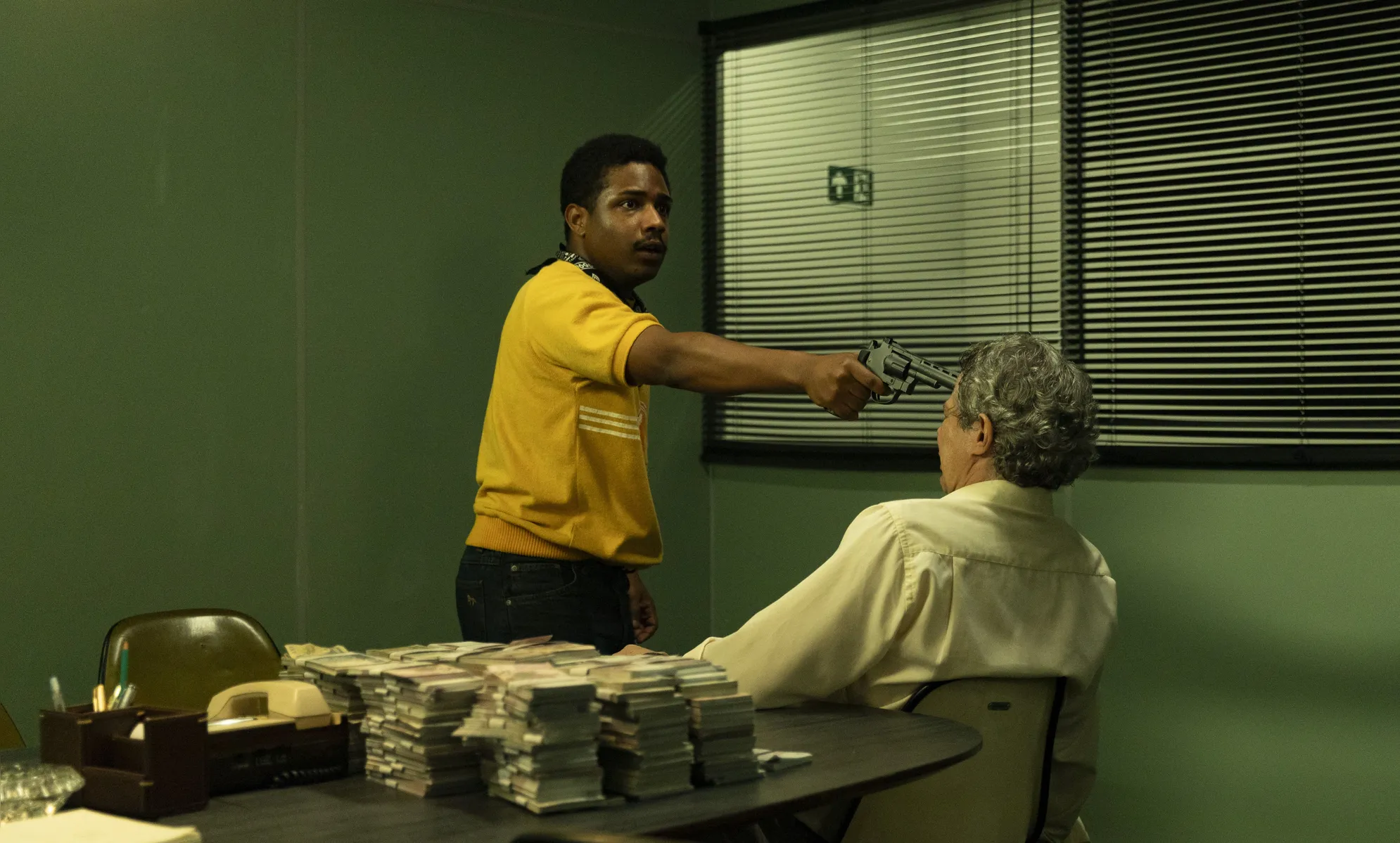 Christian Malheiros como Moreno, o mentor do assalto, pondo a mão no dinheiro na agência bancária
