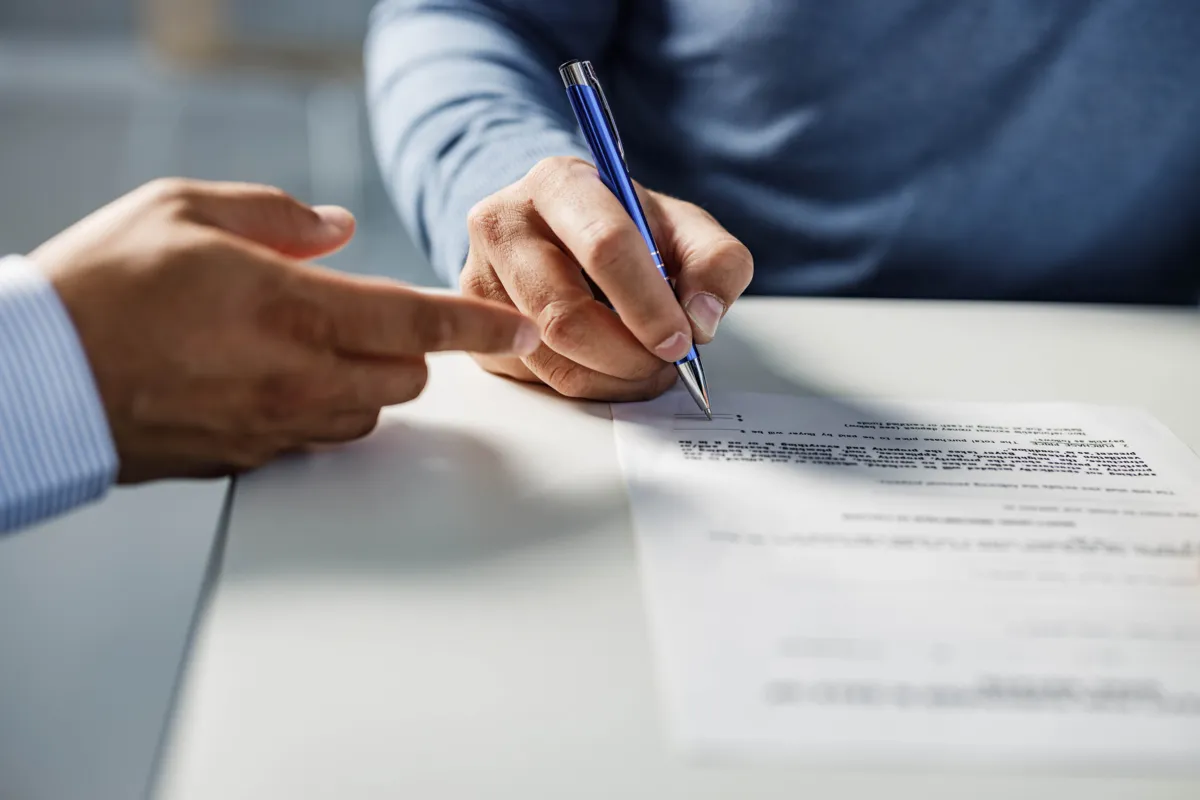 Close up of unrecognizable man signing a lease agreement on a meeting with his agent.