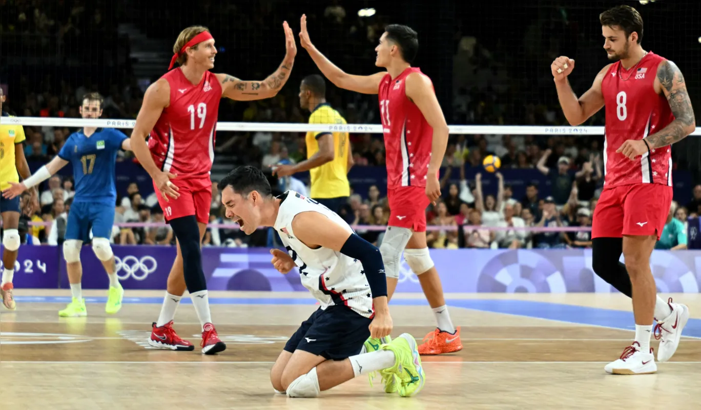 US' #22 Erik Shoji celebrates with team mates during the volleyball men's quarter-final match between USA and Brazil during the Paris 2024 Olympic Games at the South Paris Arena 1 in Paris on August 5, 2024. USA won the match 3-1. (Photo by Natalia KOLESNIKOVA / AFP)