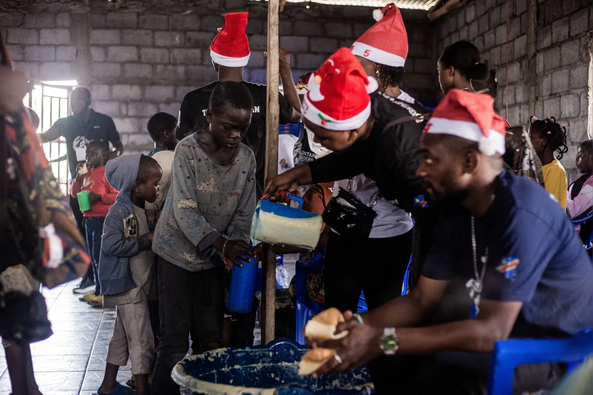 Membros da ONG Líder Voluntário distribuem alimentos antes do Natal às crianças do campo de deslocados internos de Buhimba