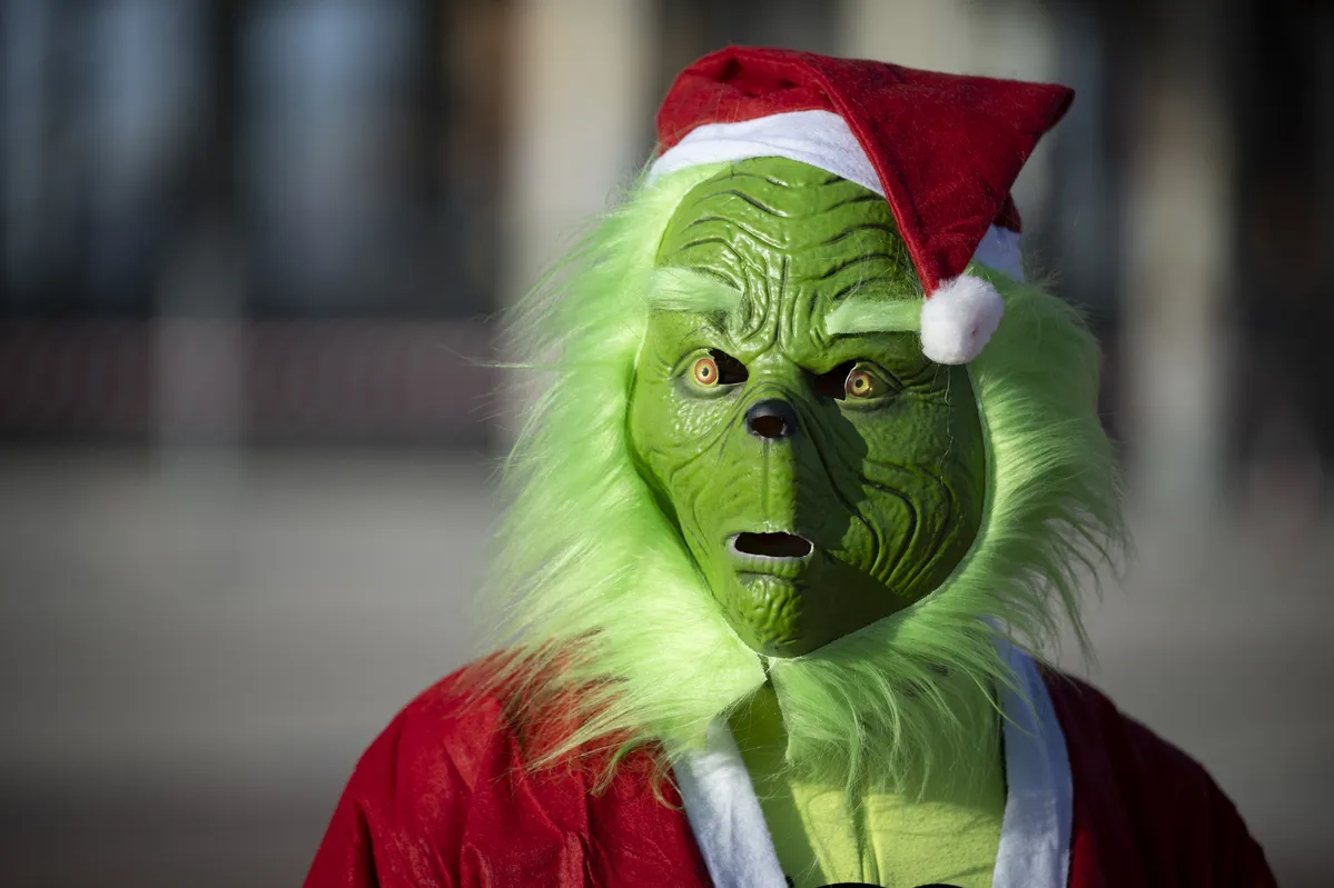 Um corredor vestido como o Grinch observa o início de uma divertida corrida de 5 km pelas ruas de Barcelona, na Espanha