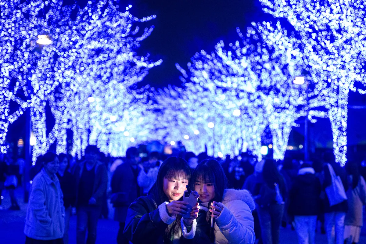 Pessoas tiram fotos com instalações de luz festivas antes do Natal no distrito de Shibuya, em Tóquio, Japão