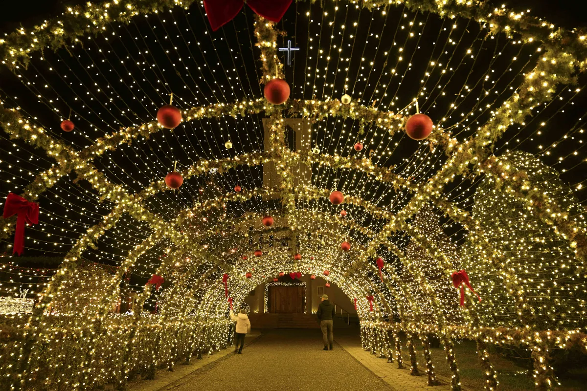 Visitantes caminham sob as decorações de Natal na igreja católica local na véspera das celebrações de Natal na vila de Petrushan, perto da cidade de Gjakova, em Kosovo