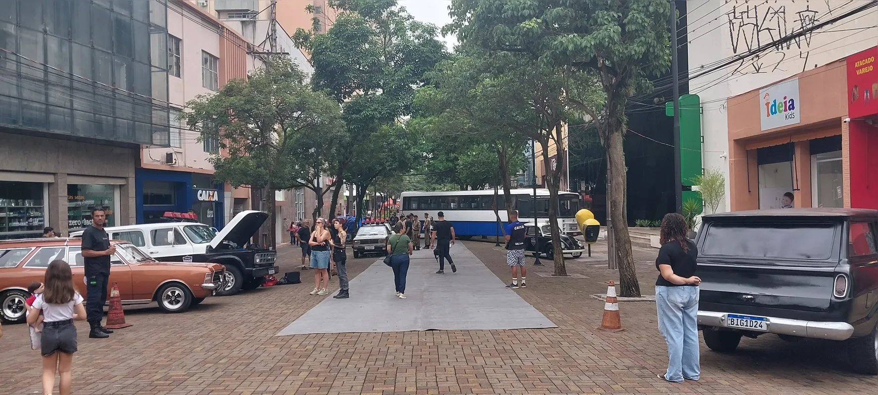 Um ônibus e uma frota de viaturas antigas estacionados no Calçadão para o início das filmagens