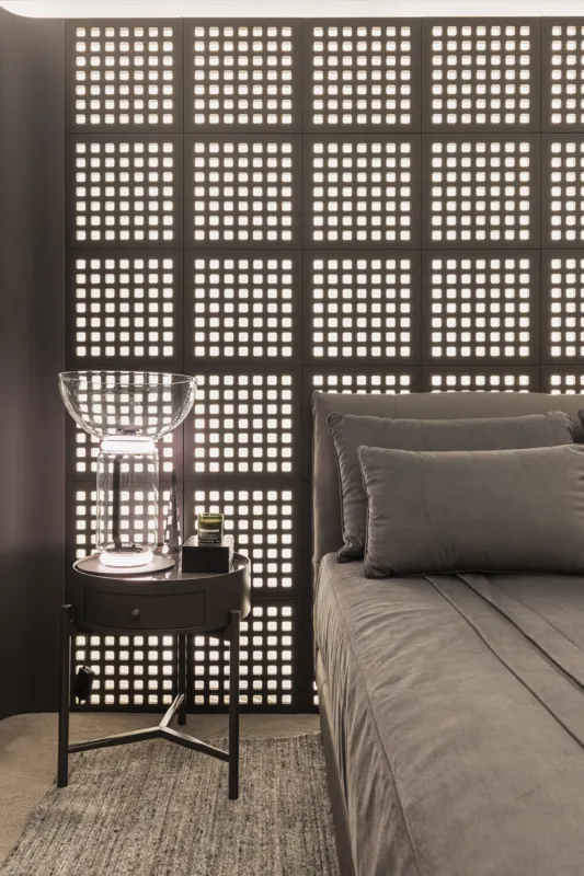 O painel muxarabi iluminado ao fundo da cama adiciona profundidade ao espaço