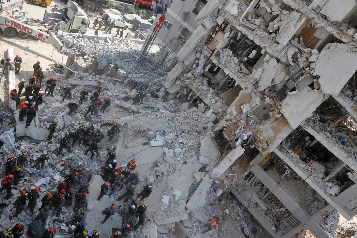 Equipes de resgate israelenses vasculharam os restos de um prédio fortemente danificado após um ataque de míssil iraniano durante a noite em Bat Yamo