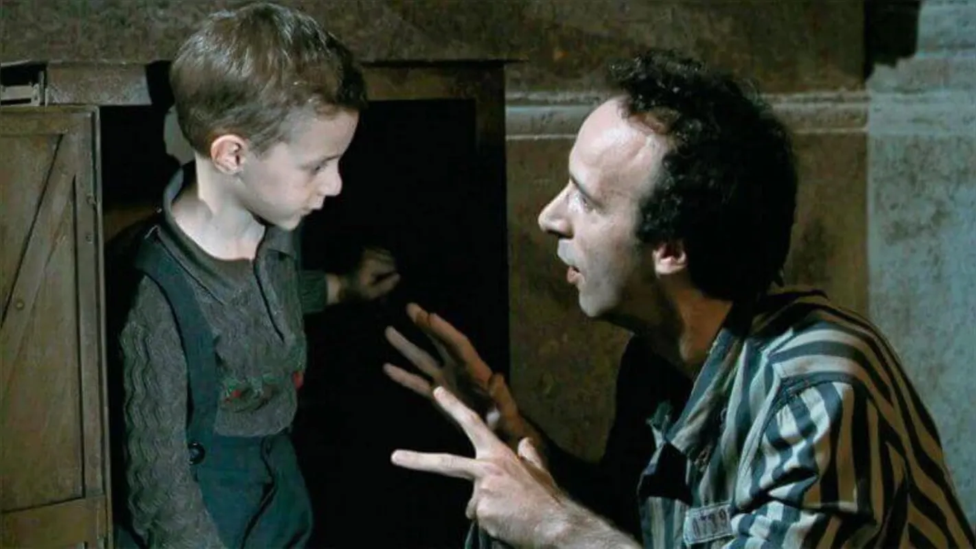 Em "A Vida é Bela" (1997), o Guido, de Roberto Benigni, está num campo de concentração com o filho e inventa um jogo fictício para tentar salvá-lo