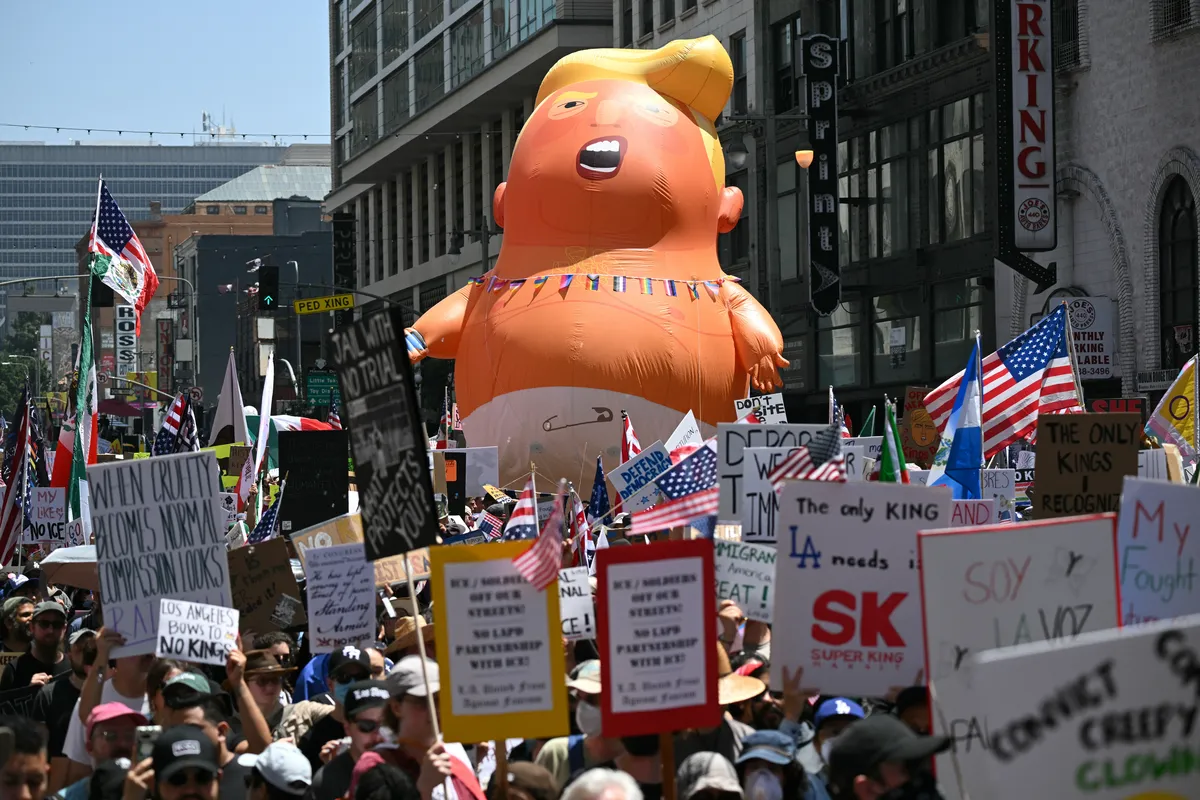 Em Los Angeles, manifestantes com bandeiras dos EUA, cartazes e um balão com o nome de um bebê Donald Trump marcharam durante o protesto nacional "No Kings" ("Sem Reis"