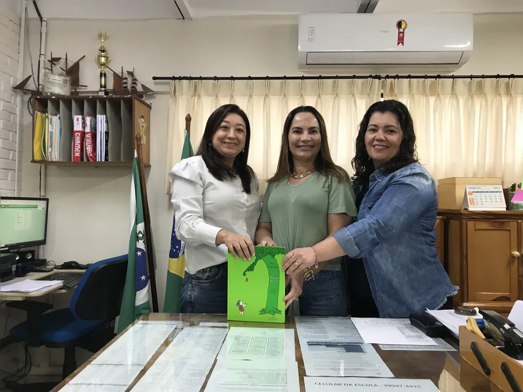 A diretora da E. M. Corveta Camaquã Nívia Pedrosa Guilhereme, a coordenadora Andreia Carvalho Moura e a secretraia Karina da Silva Santos com o livro "A Árvore Generosa" que inspirou a gincana