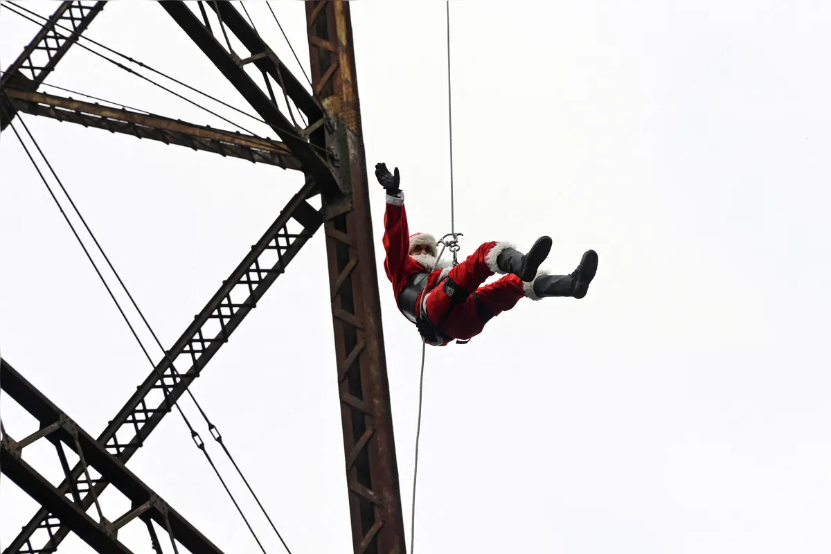 O bombeiro municipal Hector Chacon desce de rapel de uma ponte para entregar presentes a crianças na Cidade da Guatemala
