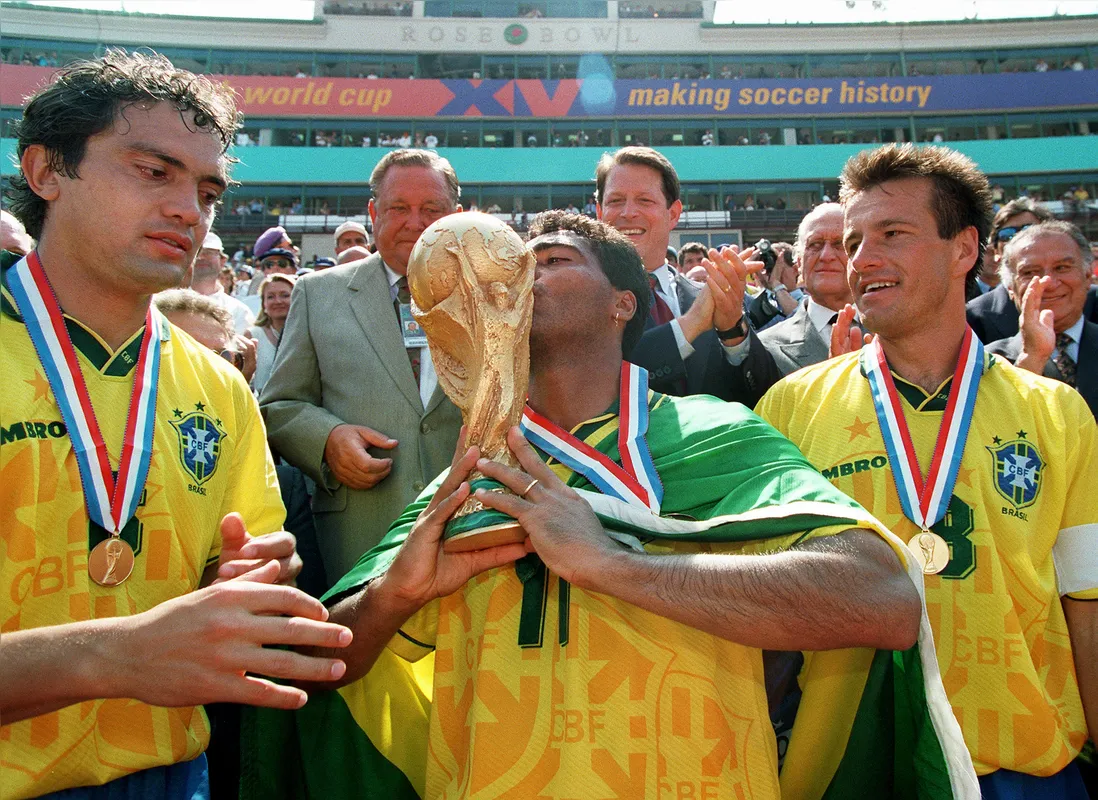 Ladeado por Branco e Dunga, Romário beija a taça que deu o tetracampeonato à seleção brasileira nos Estados Unidos em final dramática contra o Itália, decidida nos pênaltis