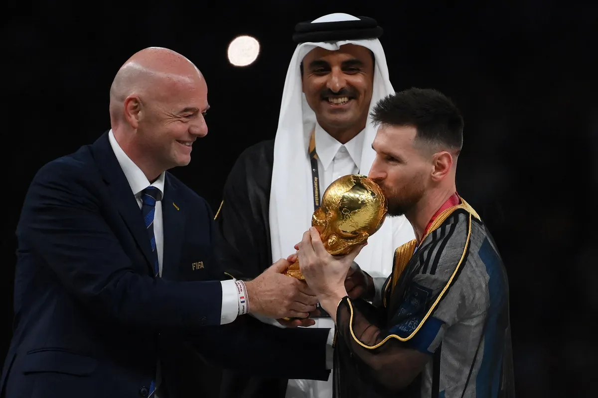 (FILES) Argentina's forward #10 Lionel Messi kisses the World Cup trophy as FIFA President Gianni Infantino and Qatar's Emir Sheikh Tamim bin Hamad al-Thani look on during the Qatar 2022 World Cup trophy ceremony after the football final match between Argentina and France at Lusail Stadium in Lusail, north of Doha on December 18, 2022. After four failed attempts, the fifth time was the charm, and Lionel Messi, one of the greatest footballers in history, was finally able to lift the World Cup, leading Argentina to their third title, despite the team?s struggles, which included having to overcome a surprise defeat in their opening match against Saudi Arabia (2?1). (Photo by FRANCK FIFE / AFP)