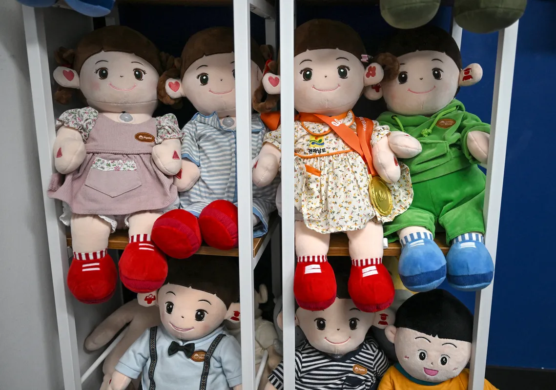 Fabricada com materiais macios, a boneca é programada com diálogos, faz pedidos e pede aos usuários que acariciem sua cabeça