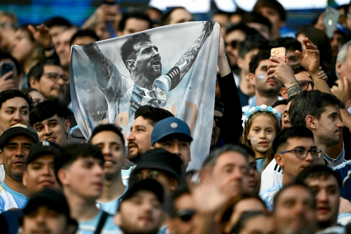 Argentine fans show a flag depicting Argentina's forward Lionel Messi ahead of the international friendly football match between Argentina and Benin at the Mas Monumental stadium in Buenos Aires on October 6, 2026. Argentines will bid farewell to Lionel Messi with a huge "thank you" themed send-off in Buenos Aires, where the legendary captain will end his more-than-two-decade international career with a friendly against Benin. (Photo by Luis ROBAYO / AFP)