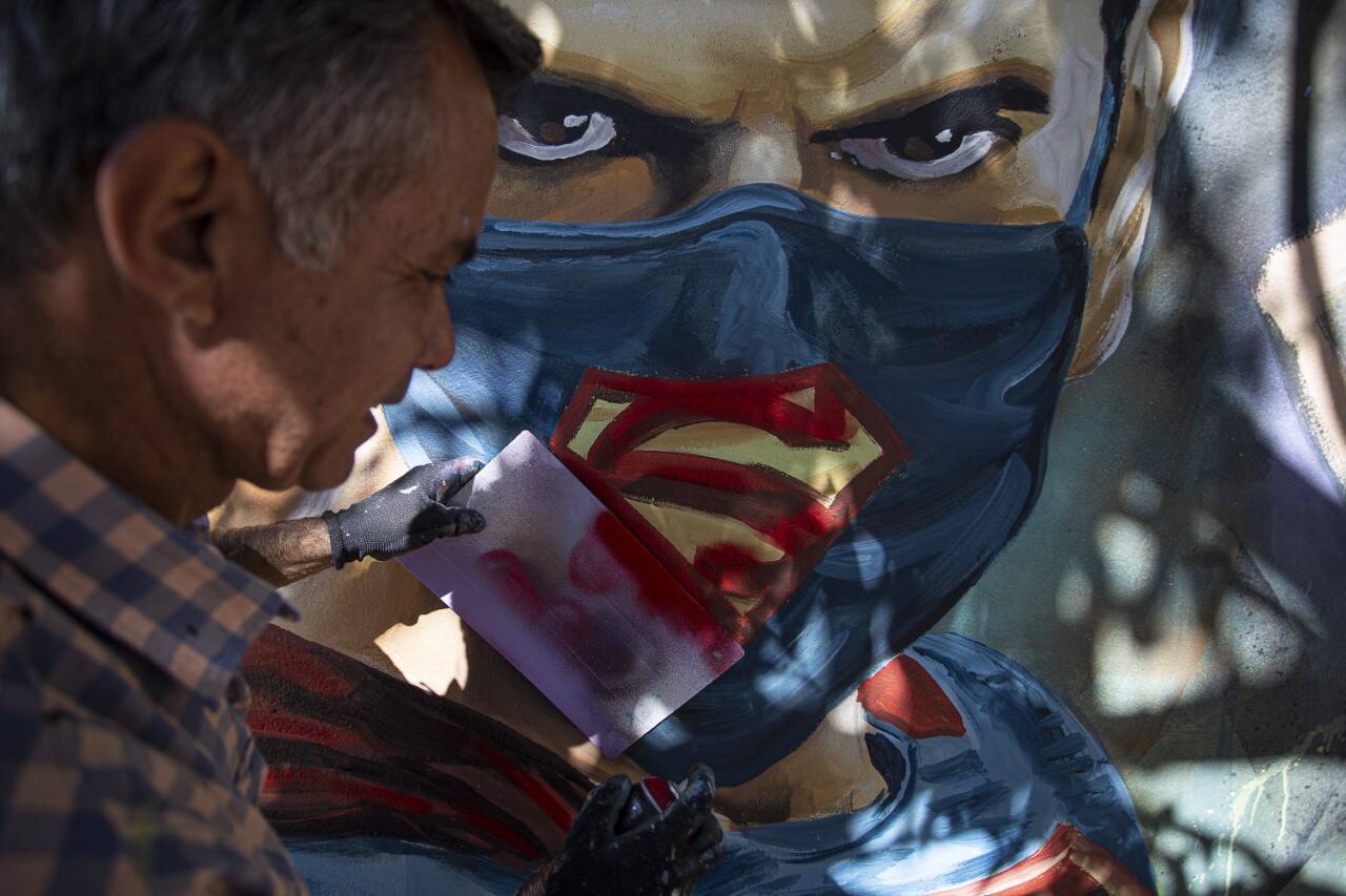 Jota Dias grafitando o Superman de máscara: "Que somos nós pra ignorar a pandemia?" , pergunta o artista